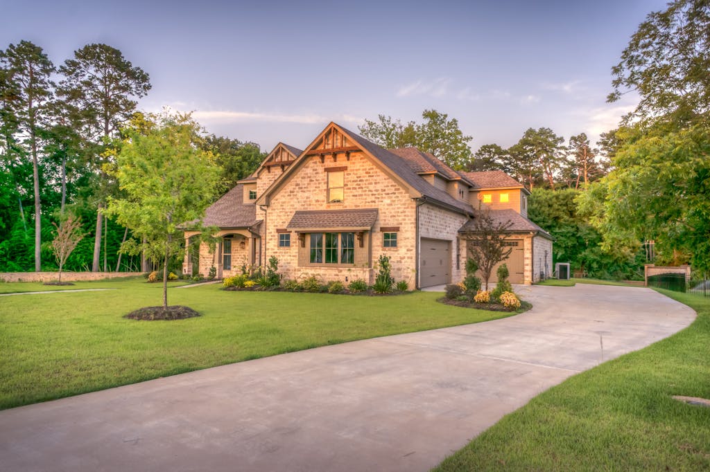 Elegant stone family home surrounded by trees, lush lawn, and vibrant garden.